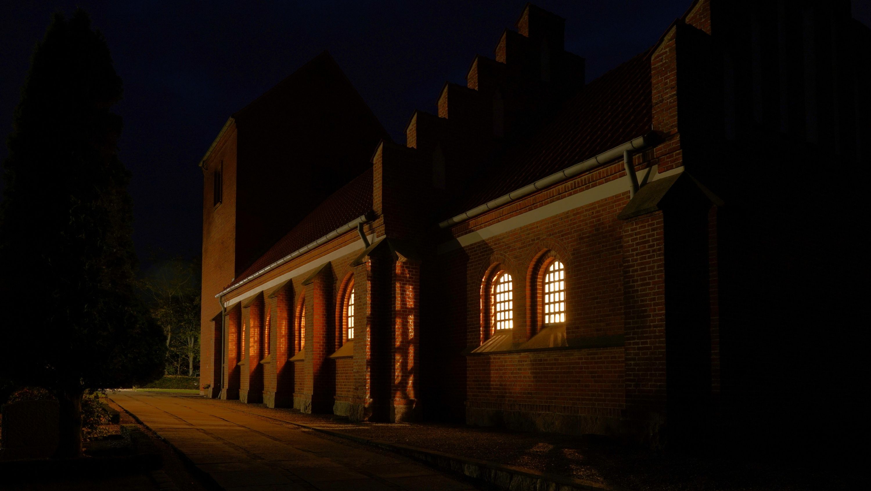 Dorf kirke i mørket med lys i vinduerne